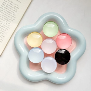 Set of seven colorful translucent glass phone grips on a stylish ceramic tray