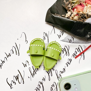 Detail of cute green silicone shark phone accessories paired with aesthetic floral background