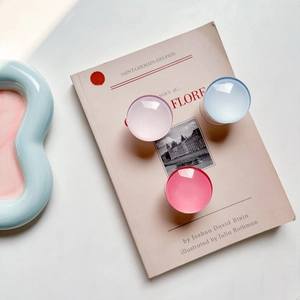Detail of round glass phone grips in pink and blue on a metal expandable base