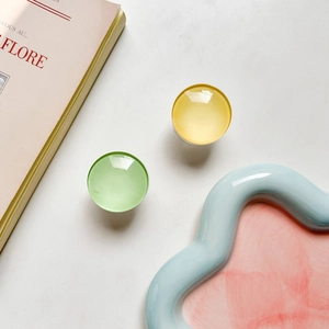 Macro detail of round glass phone grips in light green and lemon yellow with metal base