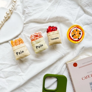 Detail shot of miniature resin pizza, baguette and tomato phone grips on white fabric