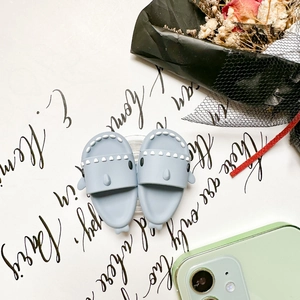 Close-up of cute light blue shark-shaped phone grips with white jagged teeth detail