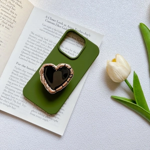 Detail of green phone case featuring a metallic gold-edged heart grip on a book