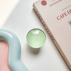 Detail of round mint green glass phone grip expanding on a stylish tray background