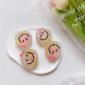 Detail of four acrylic smile face phone grips with colorful sequins and bow decorations