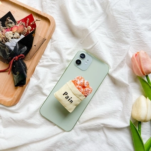 Detailed close-up of a 3D croissant bread bag phone grip on a light green case