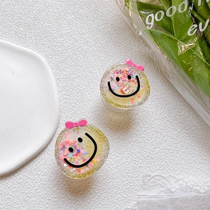 Detail of yellow smiley face phone grip with colorful sequins and pink bow decoration