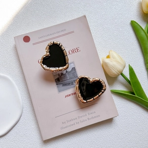 Detailed view of vintage gold bamboo texture heart stud earrings with black glaze inlay