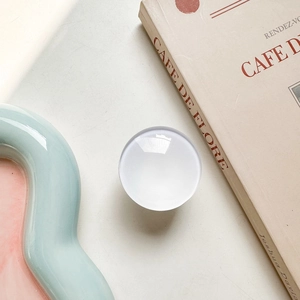 Close-up of a white circular phone grip on a minimalist desk with decorative props