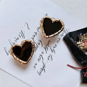 Detail of vintage heart-shaped black enamel earrings with textured gold metal frame