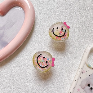 Close-up of cute glitter smiley face phone sockets with pink bow on a white textured base