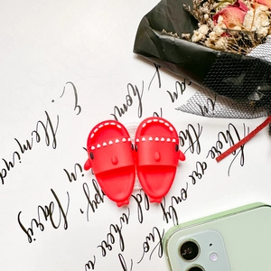 Close-up of cute red shark silicone phone grips on vintage card with red dried flowers
