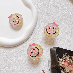 Close-up of glitter-filled resin phone grips with pink bows and smiley face designs