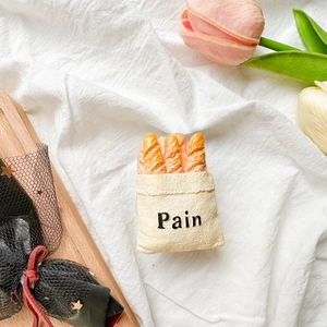 Macro shot of 3D miniature baguette bread stand with Pain text on cream cloth bag
