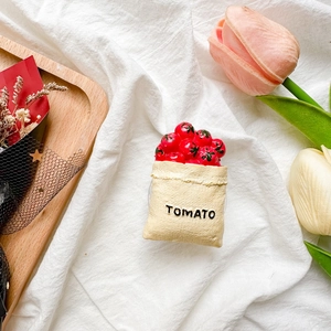 Detail shot of creative tomato-themed phone socket stand on an aesthetic fabric background