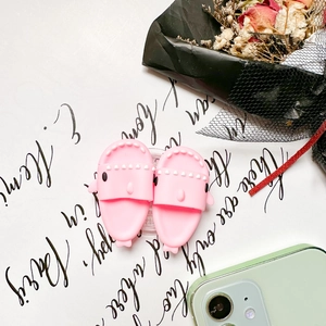 Pink shark-shaped silicone phone grip stand shown next to a pale green mobile phone