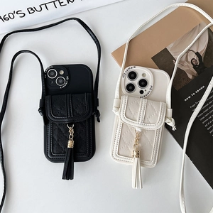 Detail of quilted leather phone case with card holder, tassel charm, and crossbody strap