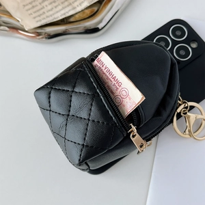 Macro view of black quilted leather mini backpack charm with gold hardware detail