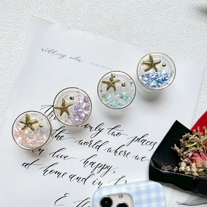 Detail of starfish phone grip with colorful shell fragments and glitter in resin
