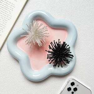 Detail view of crystal bead cluster phone grips in black and silver on a ceramic tray