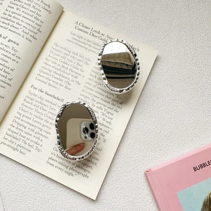 Detail of silver wavy oval vanity mirror for phone case with textured metallic finish