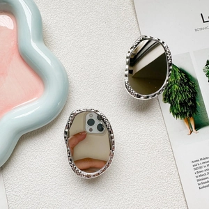 Silver pebble-shaped mirror phone grip with irregular hammered frame on white background