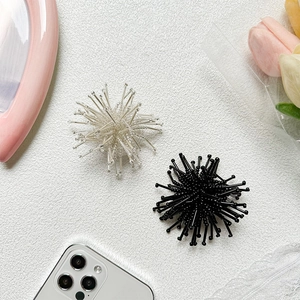 Detail of artistic sea urchin style expandable phone grip in black and transparent white