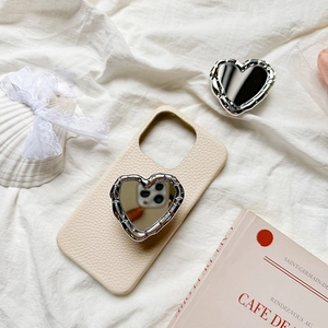 Close-up of heart-shaped mirror phone grip on cream lychee leather case with French decor