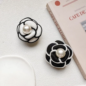 Close-up of fabric camellia phone holders with elegant pearl centers in black and white