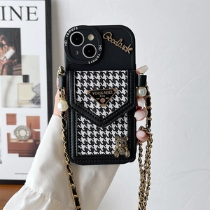 Detail of iPhone case featuring houndstooth pouch, bear charm, and gold chain crossbody strap