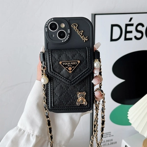 Close-up of black quilted leather phone case with teddy bear charm and crossbody chain