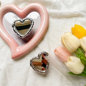 Macro shot of silver heart-shaped mirror phone grip with elegant bamboo relief texture