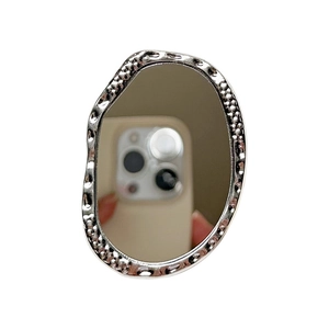 Oval silver phone grip mirror with hammered metal texture on minimalist white backdrop