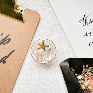 Close-up of ocean-themed phone grip with resin starfish, shells and glitter flakes