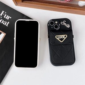 Détail de la coque iPhone matelassée noire avec strass smile et plaque métal luck