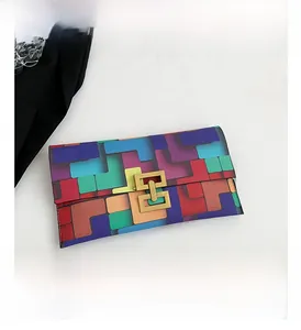 Detail of color-block envelope clutch with geometric patterns and gold interlocking clasp