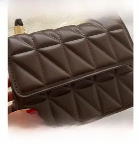 Detailed view of dark brown geometric quilted texture and gold metal clasp on handbag