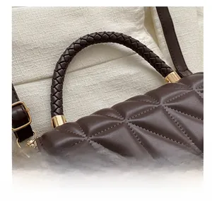 Detail of dark brown quilted shoulder bag with woven handle and gold hardware