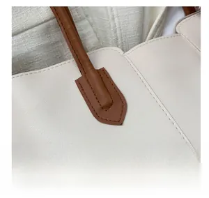 Detailed close-up of premium faux leather stitching and brown handle attachment