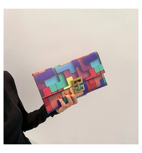 Detail of color-block envelope clutch with geometric patterns and golden H-shaped clasp