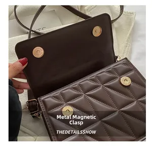 Detail view of gold magnetic buckles and quilted pattern on brown shoulder bag