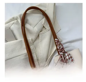 Detail of off-white tote bag handle with stylish brown checkered silk scarf wrap
