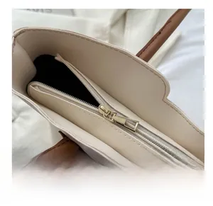 Detail of smooth golden metal zipper closure on a beige faux leather tote bag