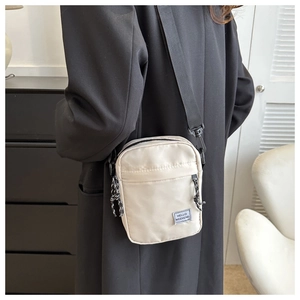 Close-up of beige nylon crossbody bag with HELLO WEEKEND label and black strap