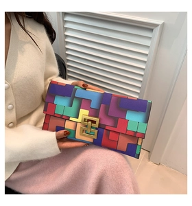 Detail of color-block geometric clutch with gold metal buckle held by model