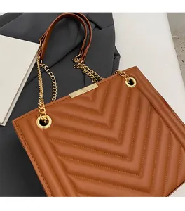 Detail of brown chevron quilted leather bag featuring gold chain strap and metal trim