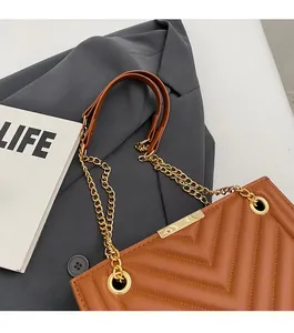 Close-up of brown quilted tote bag with V-shaped stitching and golden metal chain strap