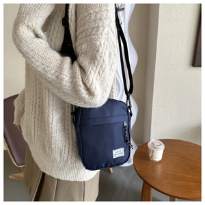 Detail of navy nylon crossbody bag featuring Hello Weekend label and adjustable strap