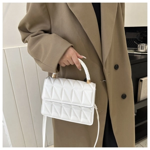 Detail of white quilted crossbody bag with woven handle and gold-tone hardware accents