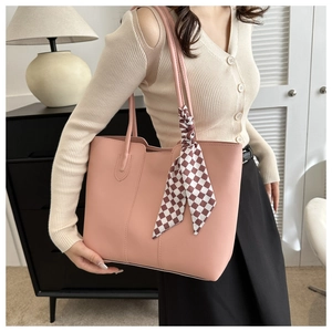 Pink faux leather tote bag with stylish plaid scarf detail shown in a cozy home setting